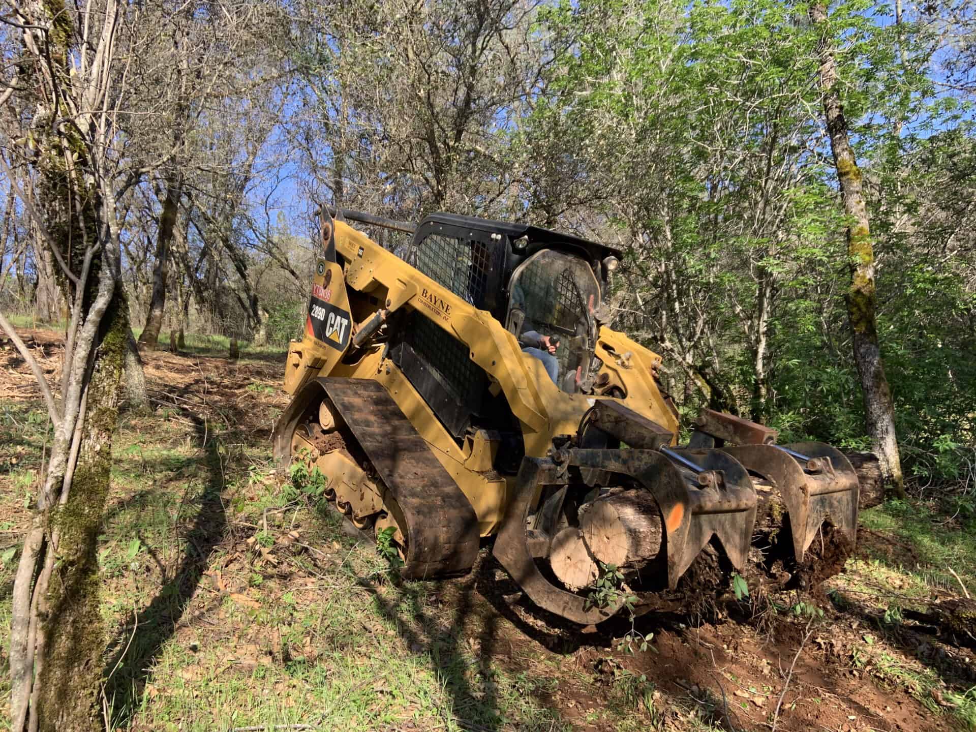 Small dozer on hill removing logs from property